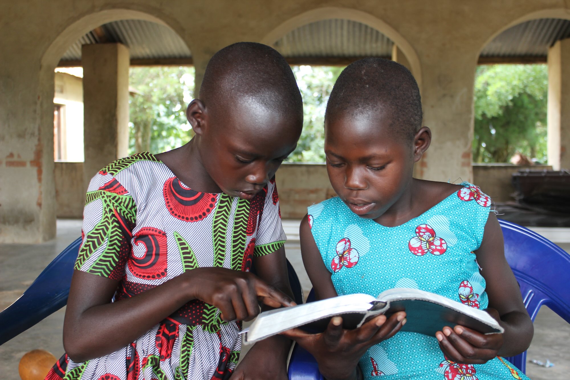 two sponsored children reading bible together